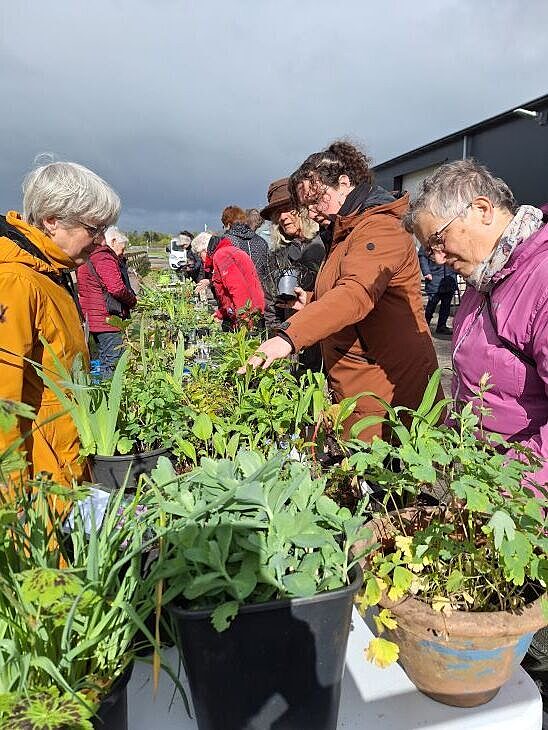 Tafel staat vol met planten mensen staan eromheen