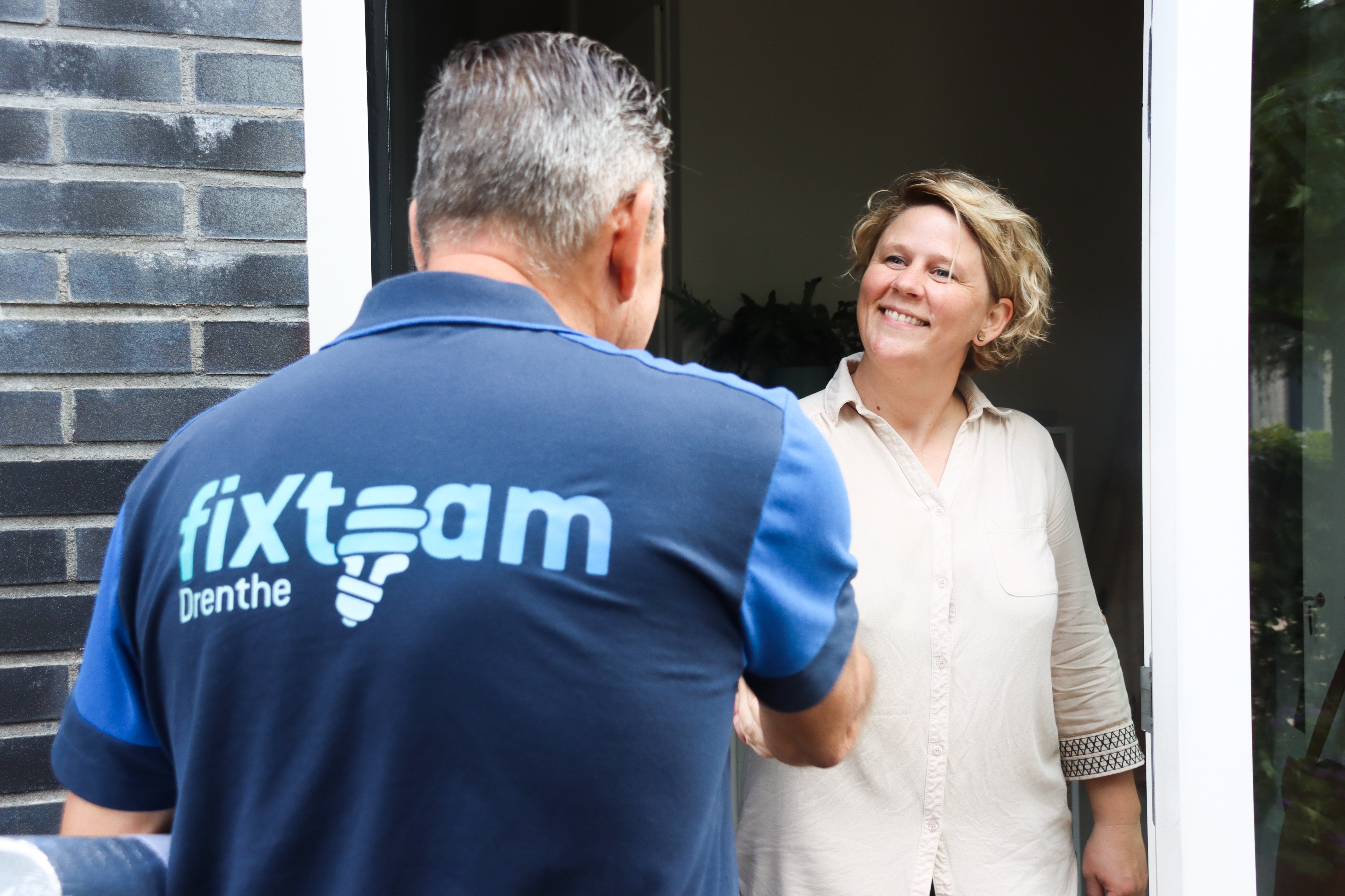 Man schut vrouw de hand in deuropening van huis