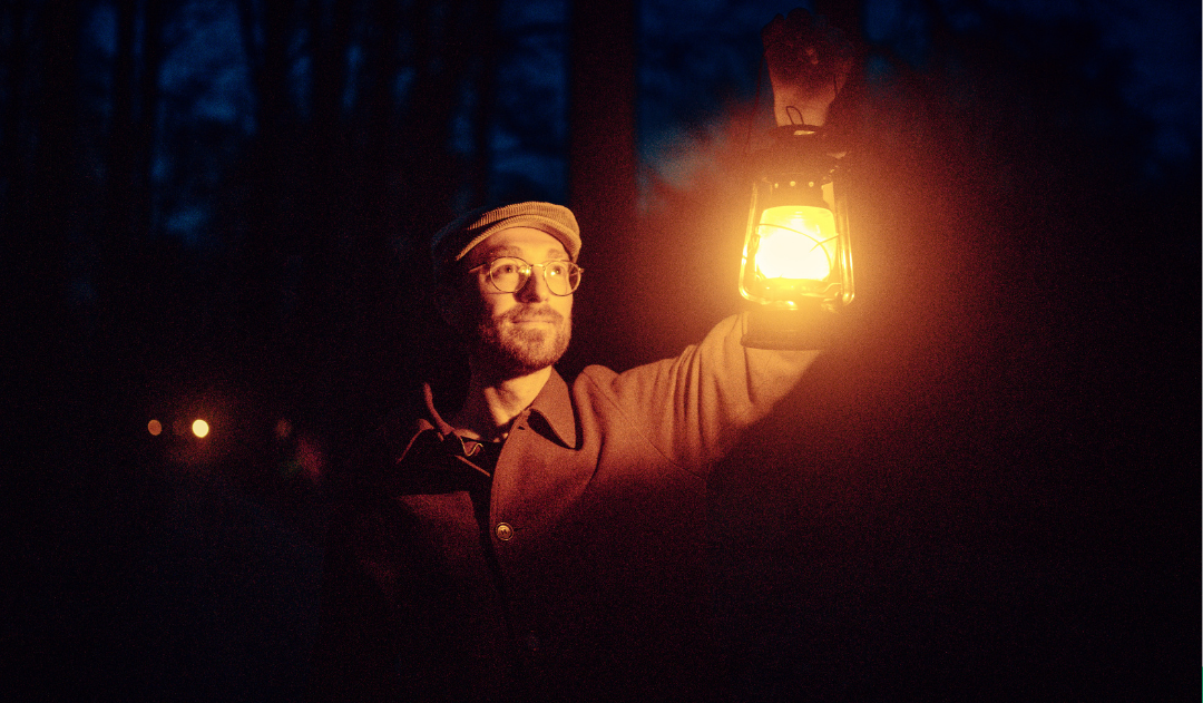 Man in het donker houdt lamp vast