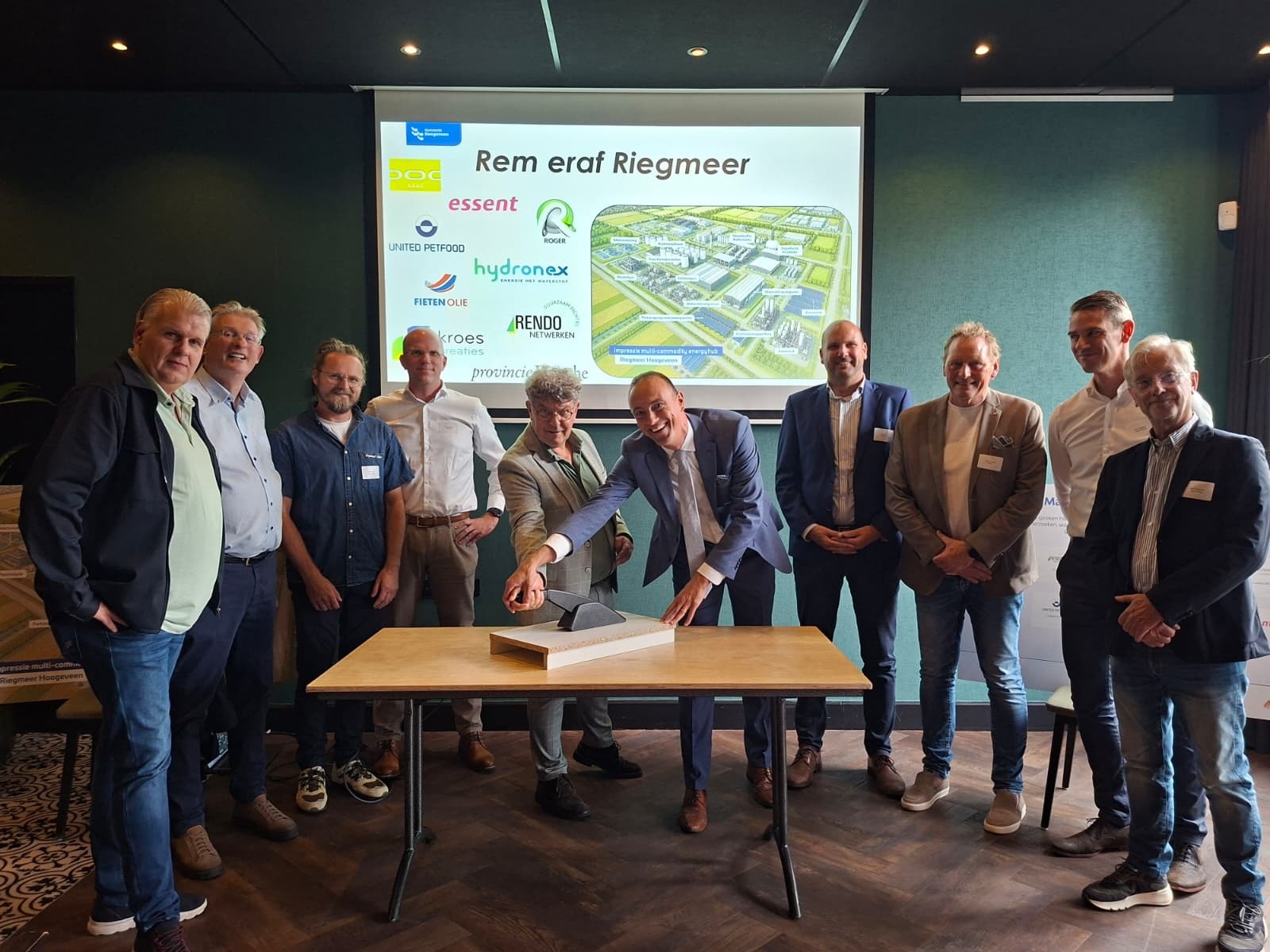 Mannen staan rondom tafel voor presenatiescherm