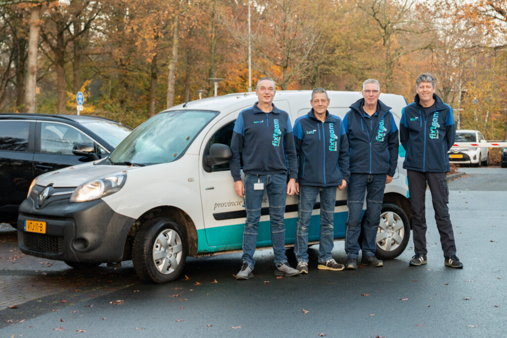 Vier mannen van het fixteam staan voor een auto